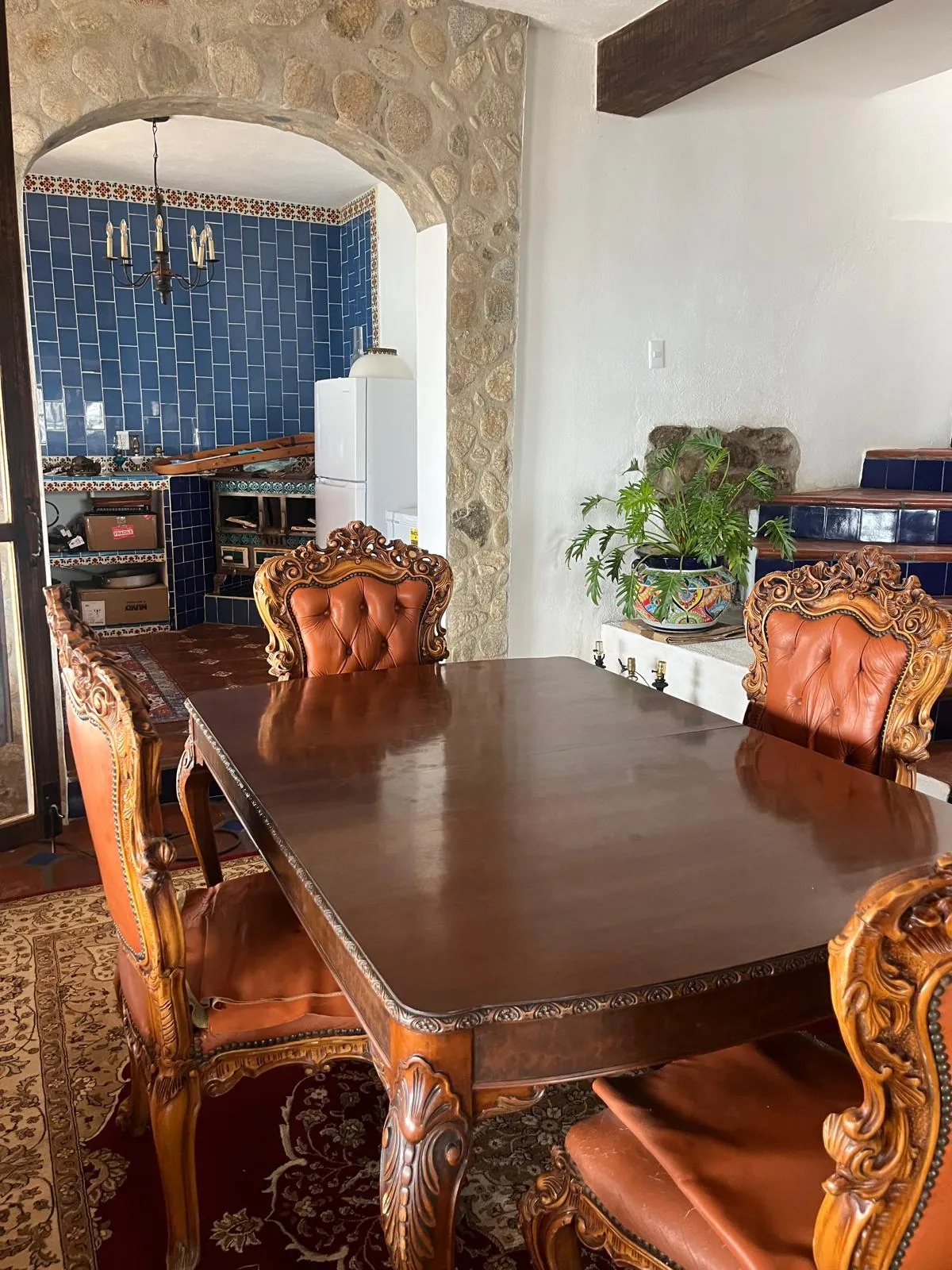 Comedor con mesa de madera y cocina de talavera azul al fondo